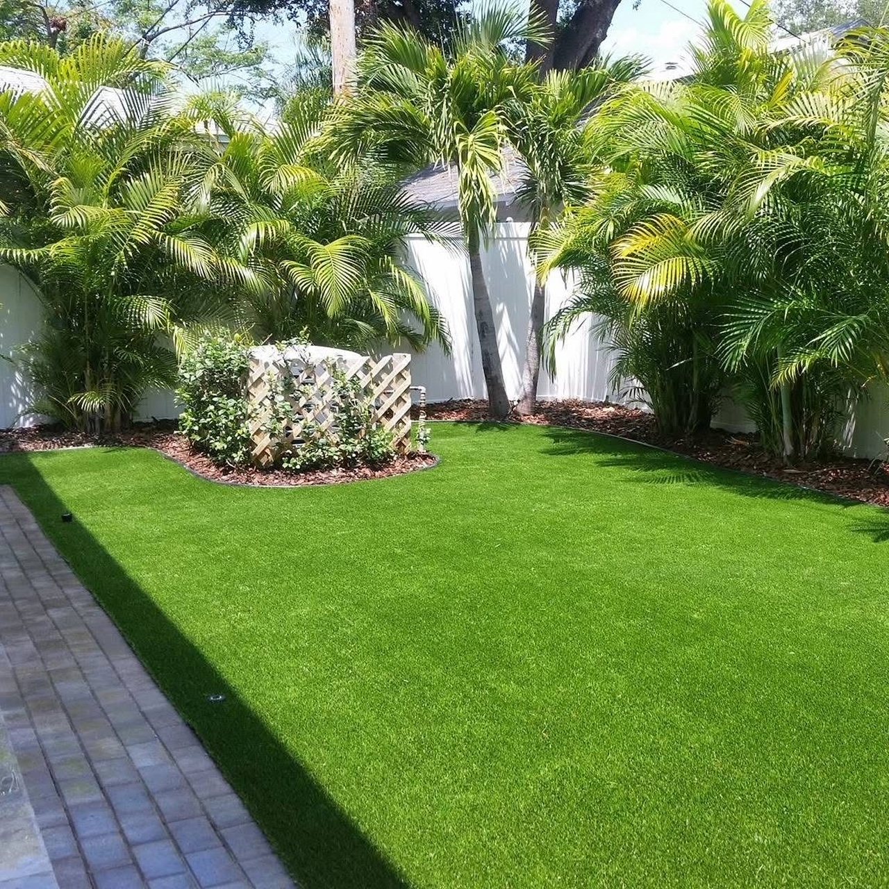 Backyard turf framed by palms and a paver border