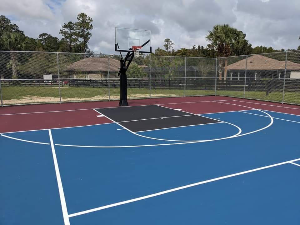 Blue and red basketball and pickleball court with a single hoop