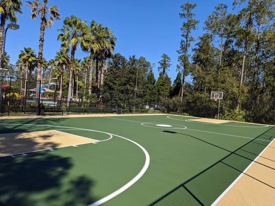 Green basketball court with tan key under palms