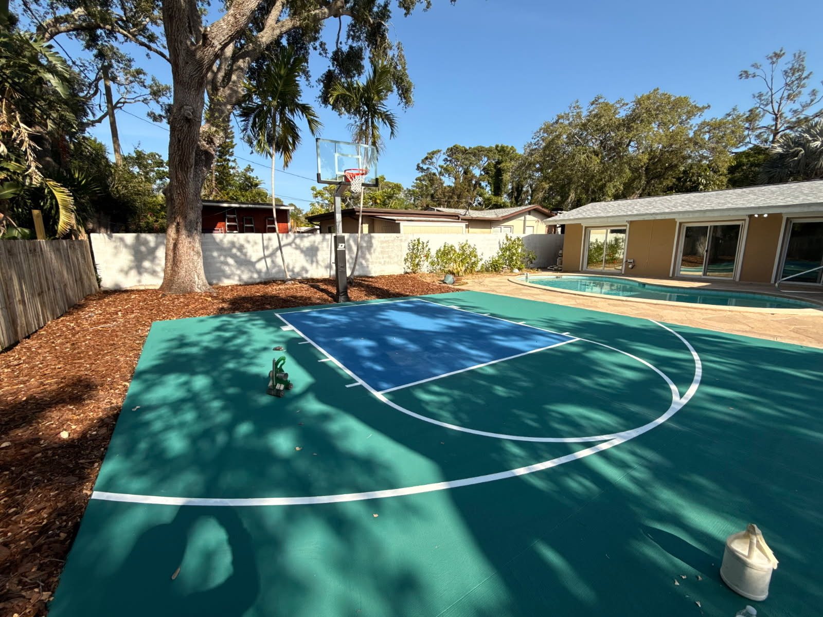 Teal and blue backyard half court with hoop