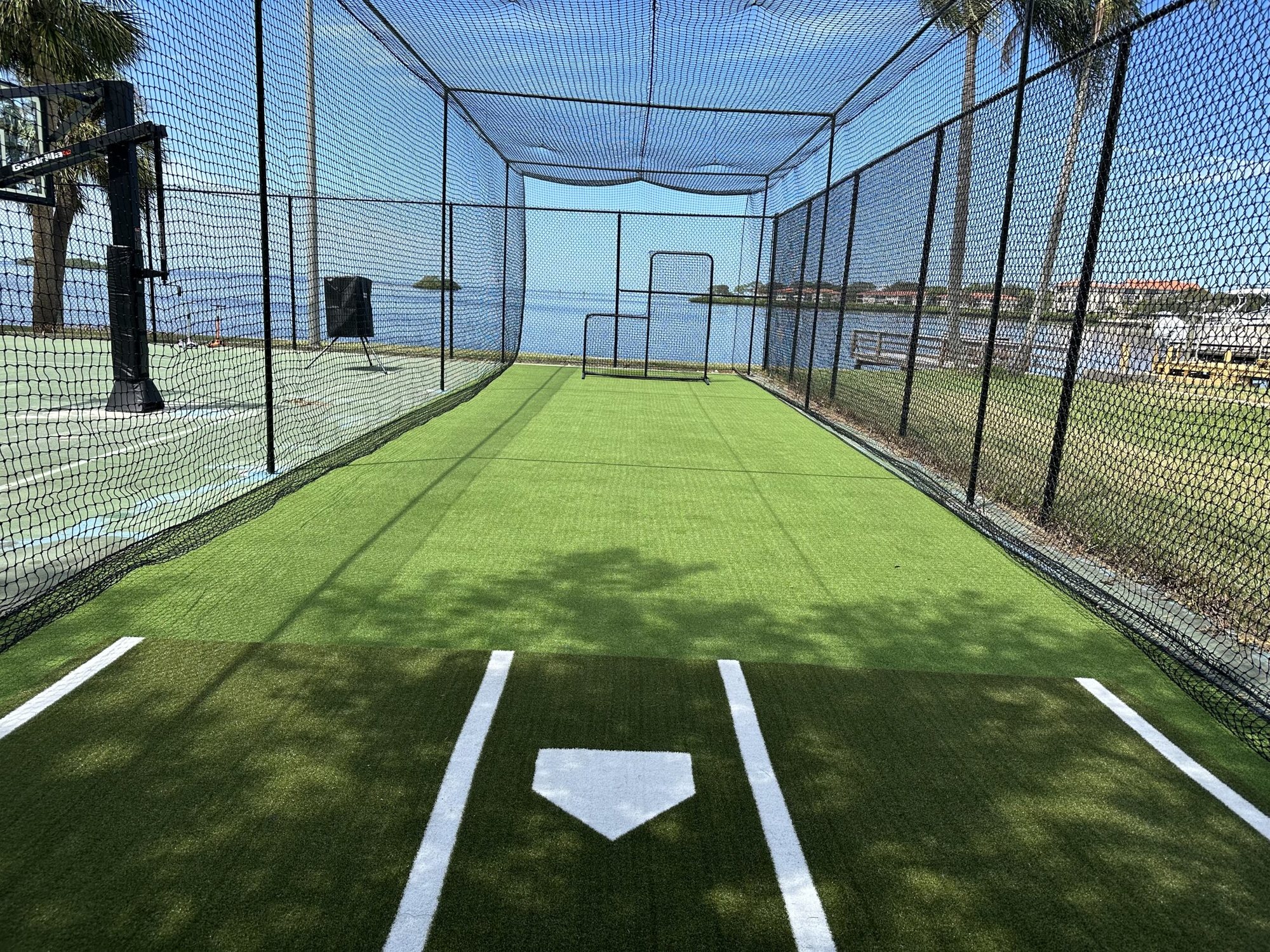 Turf batting cage with painted home plate by the water