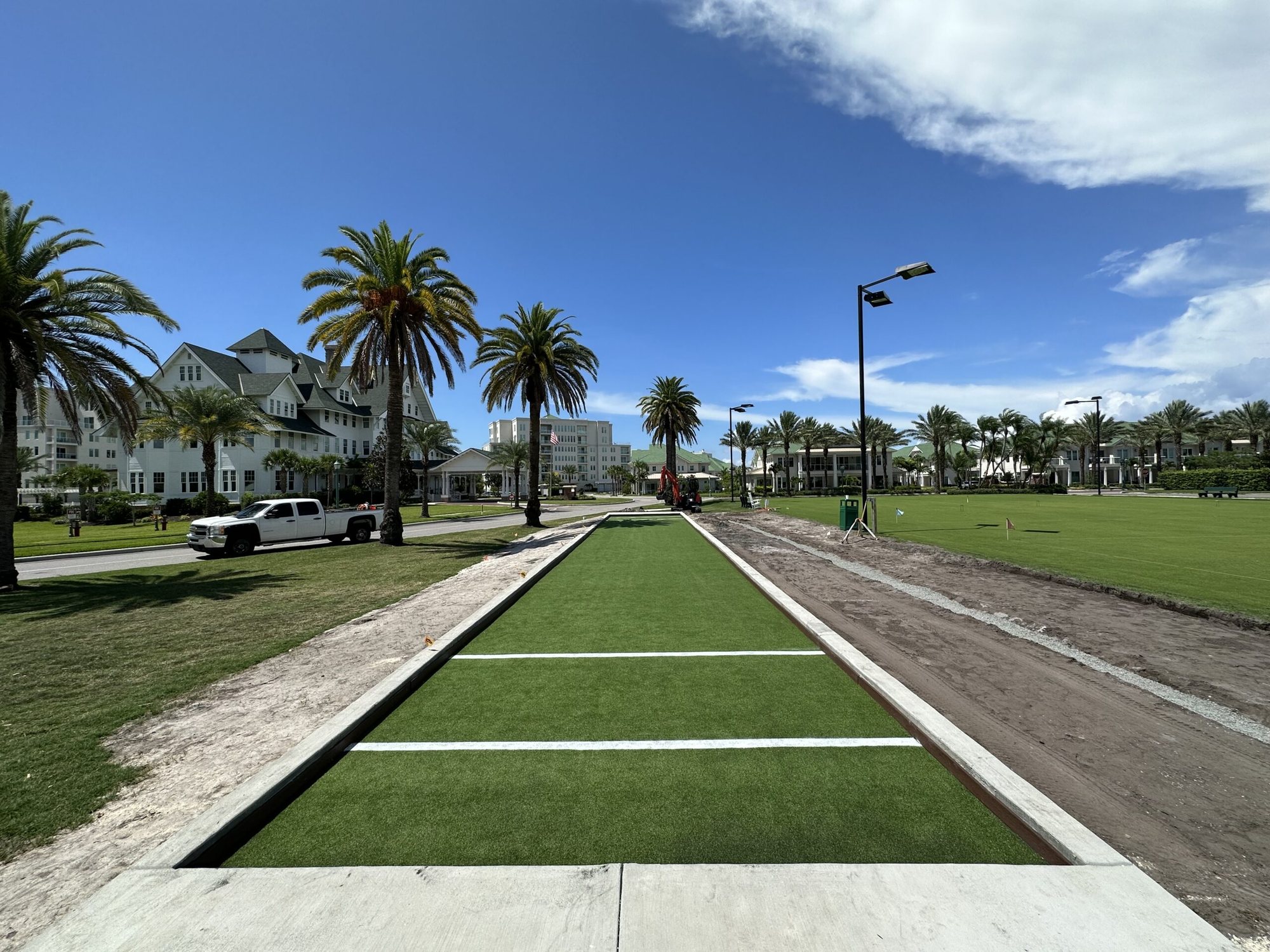 Turf bocce lane with light poles along a waterfront community