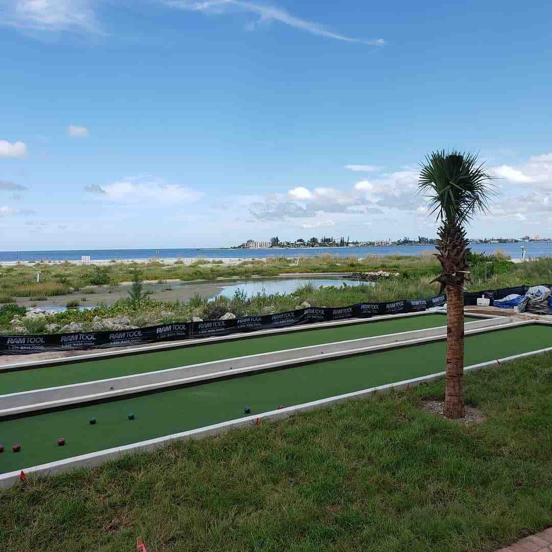 Turf bocce court with a palm tree beside open water