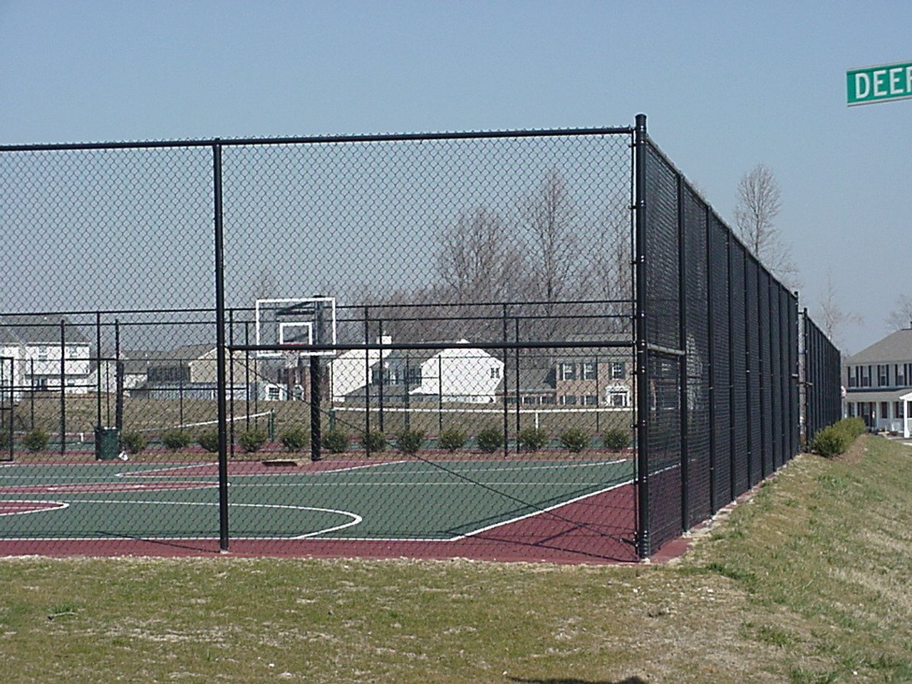 Black chain link fence enclosing an outdoor basketball court