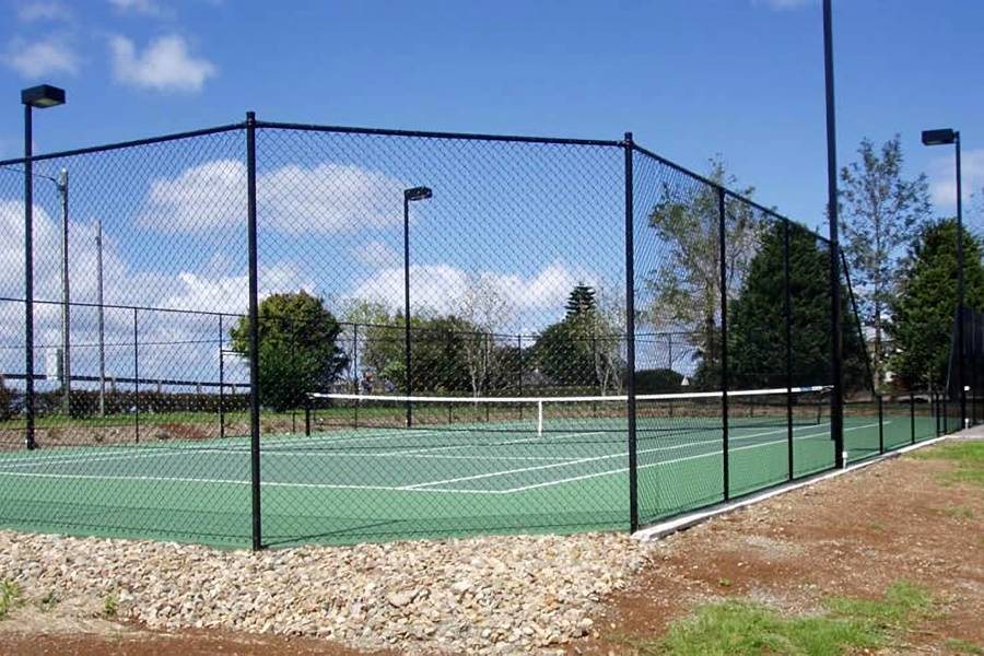 Chain link fence along a tennis complex with a brick walkway