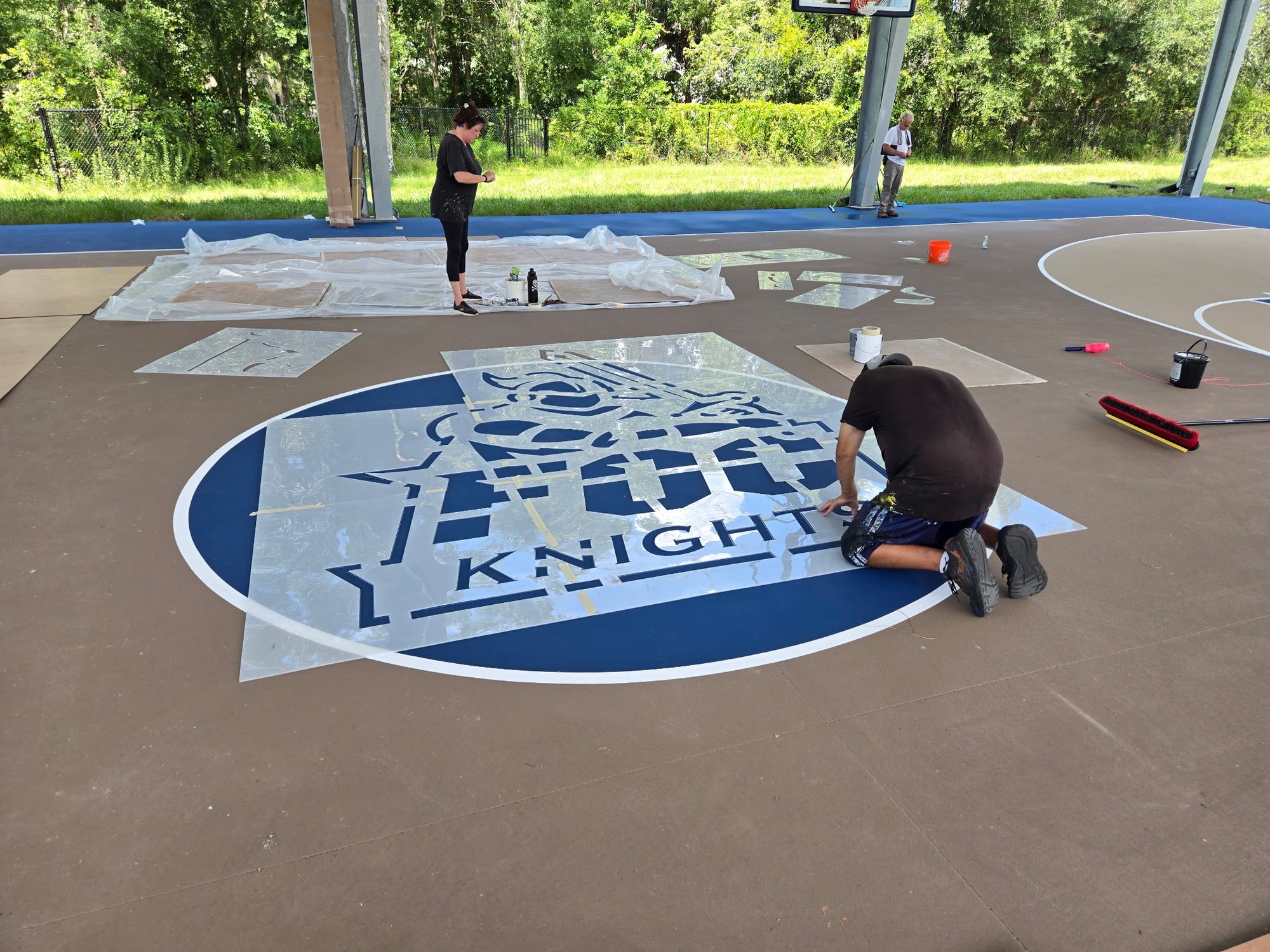 Golf Coast Sports crew laying out stencils to paint a Knights logo on a covered court
