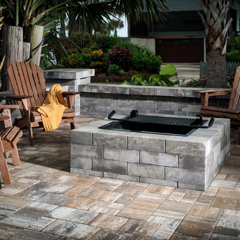 Stone fire pit with Adirondack chairs on a paver patio