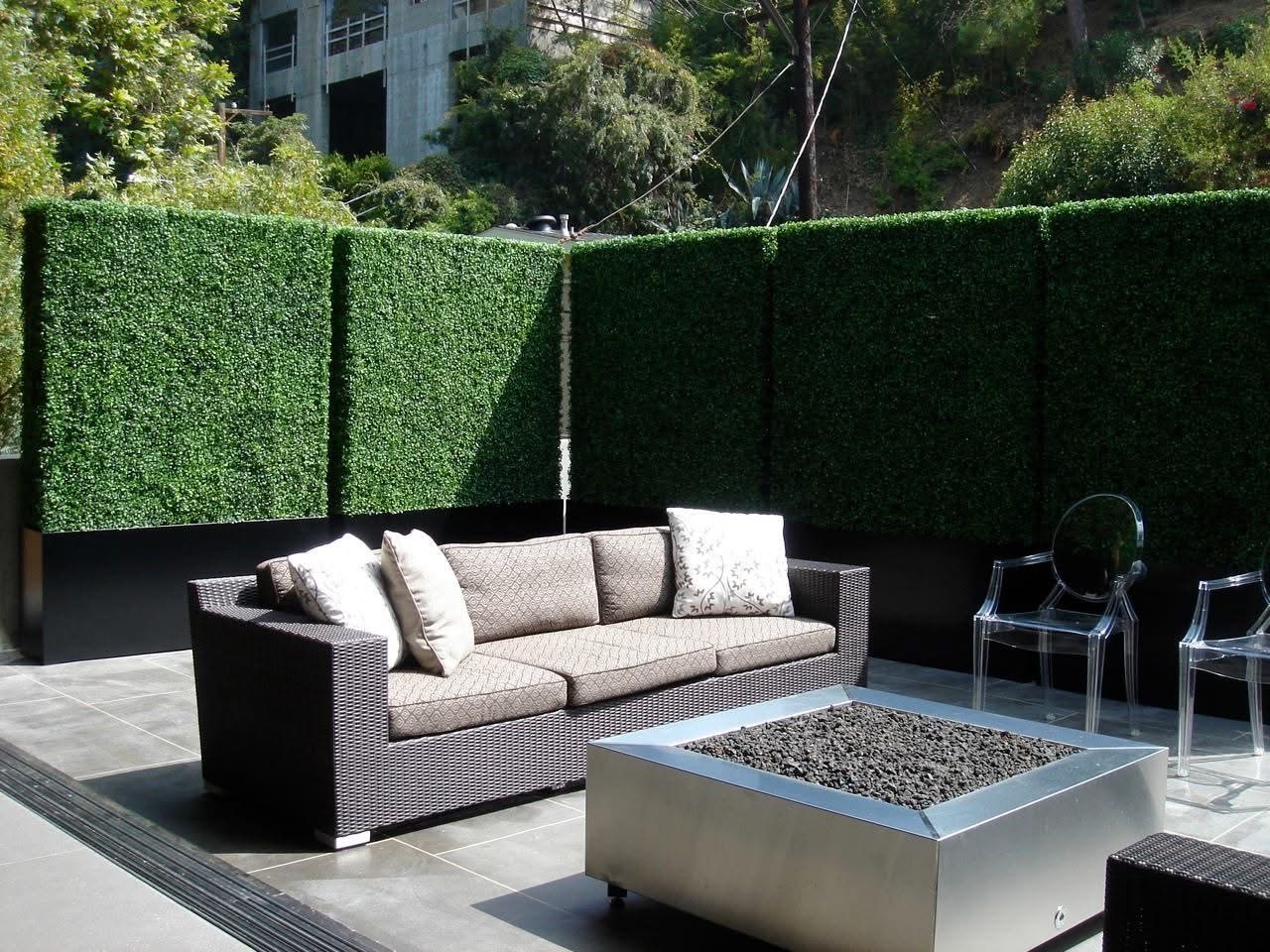 Patio lounge enclosed by tall artificial hedge privacy panels
