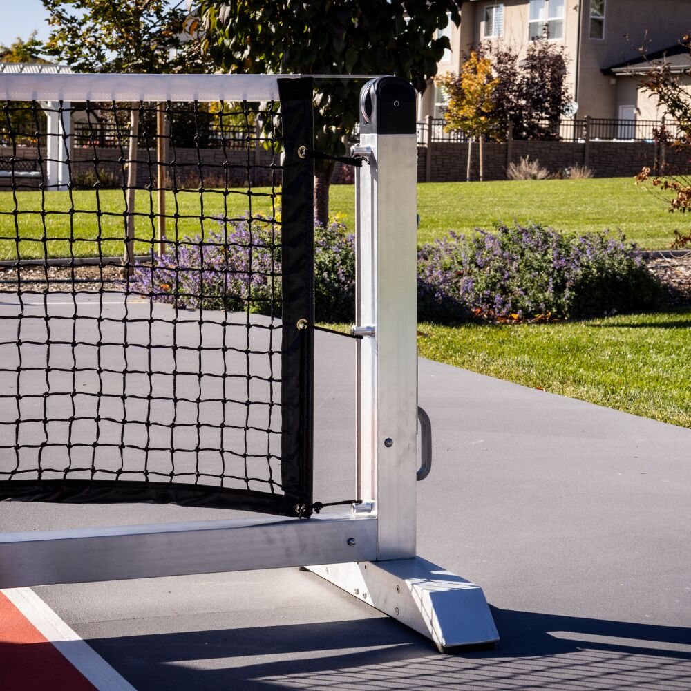 Portable pickleball net on wheels at the edge of a court