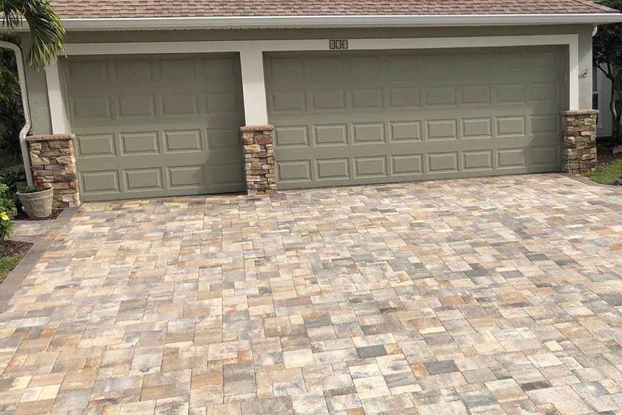 Tan paver driveway in front of a two-car garage