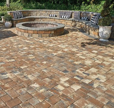 Paver courtyard with a round stone fire pit and curved seating wall