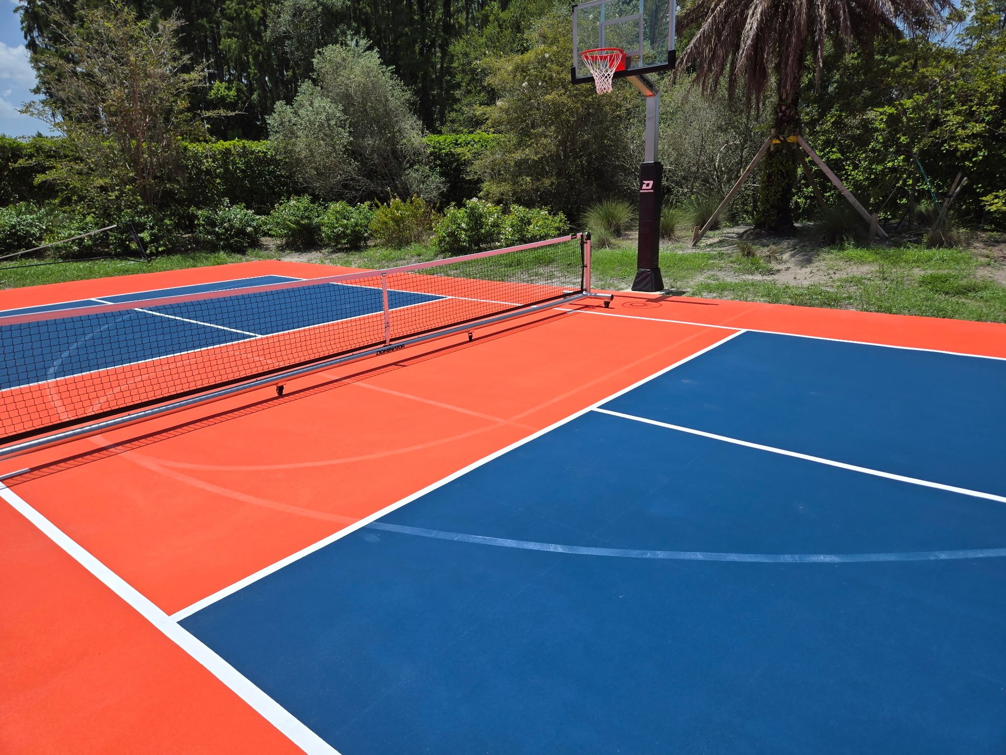 Pickleball court with net and a basketball goal at the end