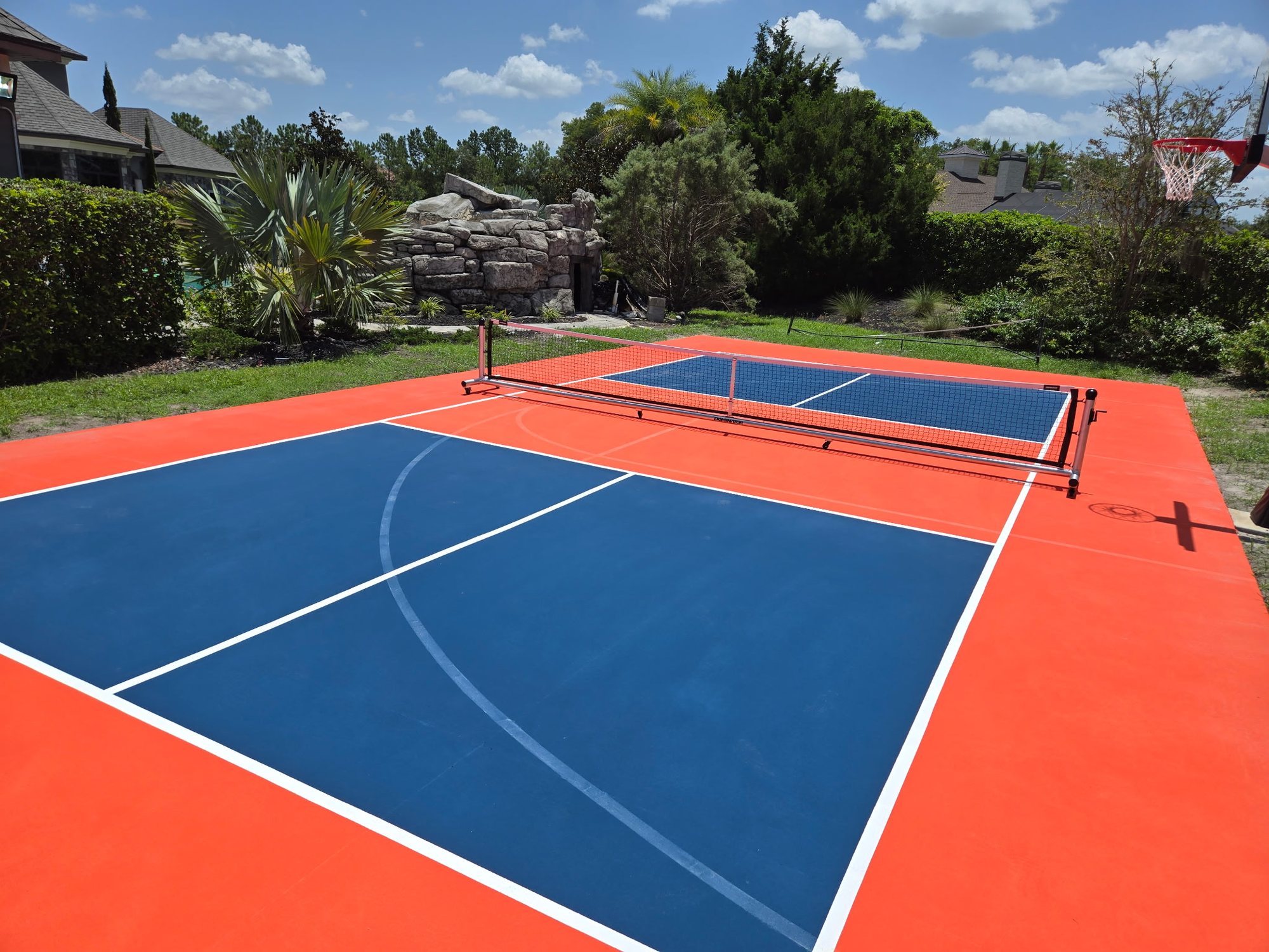 Backyard pickleball court with a blue playing surface and orange surround
