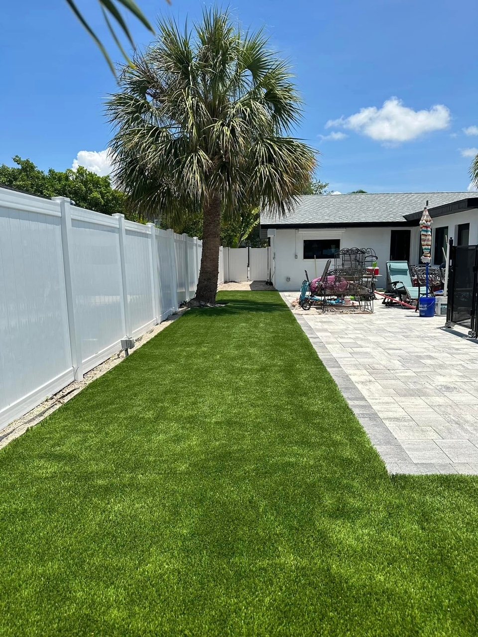 White vinyl fence along a turf side yard with a palm tree
