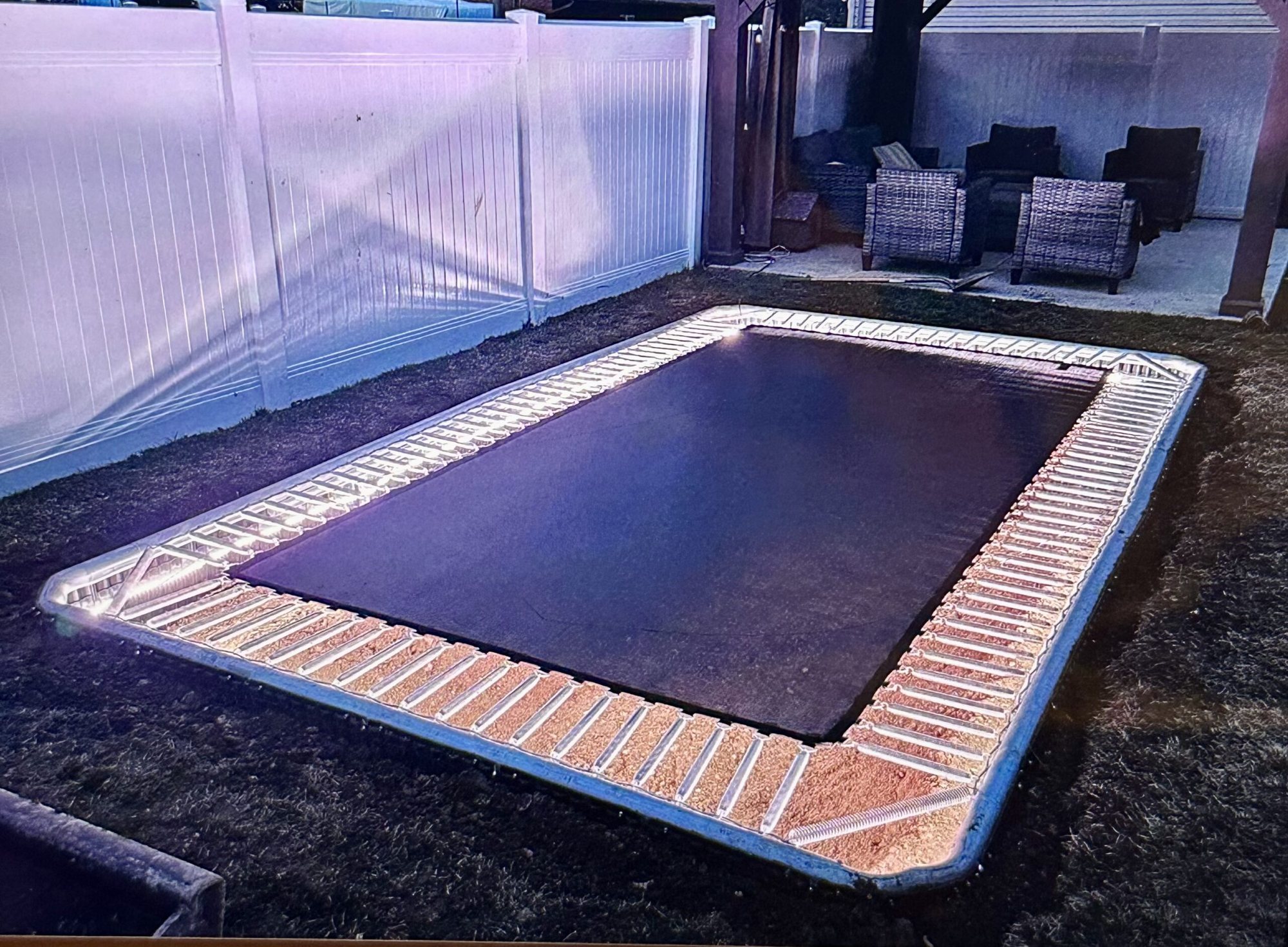 In-ground trampoline with a glowing border at dusk